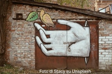 Foto di graffiti di una mano che tiene un uccello con una foglia. Foto di Stacy su Unsplash